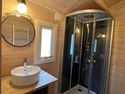Bagno rivestito in legno con lavandino, specchio tondo e doccia moderna al Drentse kap, EuroParcs Ruinen, Paesi Bassi.