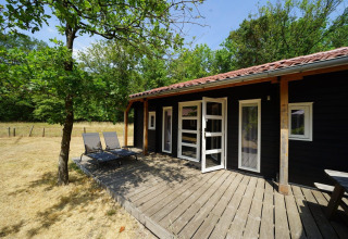 Houten terras en ligstoelen aan Drentse kap lodge bij EuroParcs Ruinen, omringd door groen.