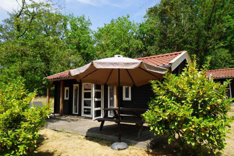 Außenansicht der Drentse kap-Lodge im EuroParcs Ruinen, Niederlande, mit Terrasse, Tisch und Sonnenschirm.