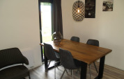 Comedor en Forest Lodge de EuroParcs Ruinen, Países Bajos, con mesa de madera y sillas grises modernas.