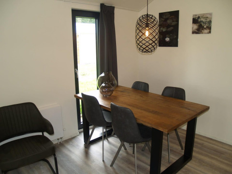 Eethoek in Forest Lodge van EuroParcs Ruinen, Nederland, met houten tafel en grijze stoelen.