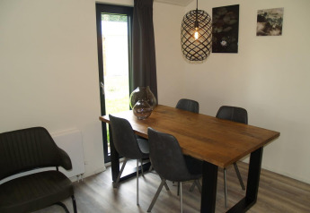 Comedor en Forest Lodge de EuroParcs Ruinen, Países Bajos, con mesa de madera y sillas grises modernas.