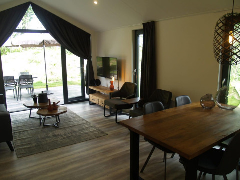 Wohnbereich der Forest Lodge im EuroParcs Ruinen, Niederlande, mit Holztisch und Blick auf die Terrasse.