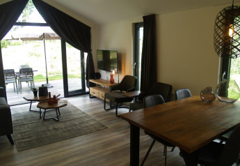 Wohnbereich der Forest Lodge im EuroParcs Ruinen, Niederlande, mit Holztisch und Blick auf die Terrasse.
