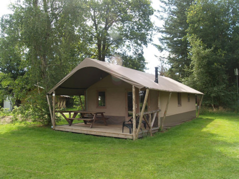 Buitenaanzicht van Four Season Lodge met overdekte veranda, picknicktafel en groene grasvelden.