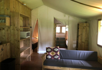 Innenraum der Four Season Lodge im EuroParcs Ruinen, Niederlande, mit rustikalen Holzmöbeln und Sofa.