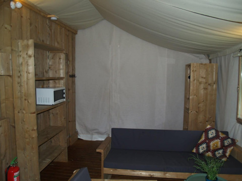 Binnenaanzicht van Four Season Lodge bij EuroParcs Ruinen met houten meubels, bank en magnetron.