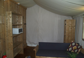 Vue intérieure du Four Season Lodge à EuroParcs Ruinen avec mobilier en bois, canapé et micro-ondes.