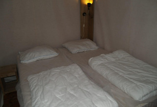 Cama doble con dos edredones individuales y almohadas en Four Season Lodge, EuroParcs Ruinen, Países Bajos.