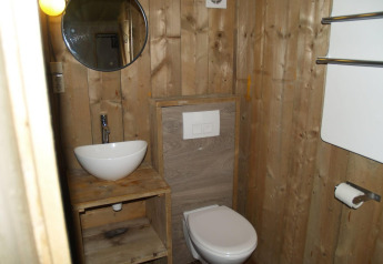 Salle de bain en bois avec lavabo, miroir et toilettes à Four Season Lodge, EuroParcs Ruinen, Pays-Bas.