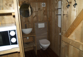 Bagno in legno con lavandino, specchio, WC e microonde presso Four Season Lodge di EuroParcs Ruinen, Paesi Bassi.