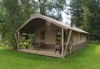 Buitenzicht van Four Season Lodge bij EuroParcs Ruinen in Nederland met veranda, zitbank en groene tuin.