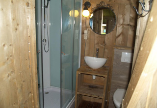 Baño con ducha de vidrio, lavabo y paneles de madera en Four Season Lodge, EuroParcs Ruinen, Países Bajos.