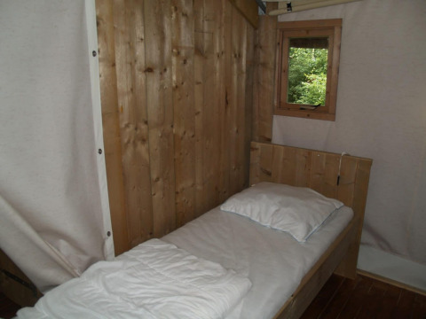 Eenvoudige houten wand en eenpersoonsbed met wit beddengoed in Four Season Lodge, EuroParcs Ruinen.