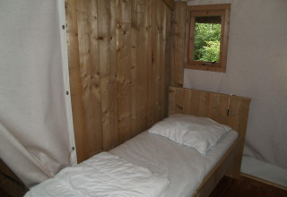 Lit simple avec draps blancs et murs en bois dans la Four Season Lodge à EuroParcs Ruinen, Pays-Bas.
