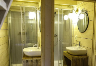 Twee identieke badkamers met douche en wastafel in houten stijl bij Glamping Family Lodge 10, EuroParcs Ruinen.