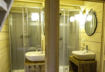 Dos baños idénticos con ducha y lavabo en un entorno de madera en Glamping Family Lodge 10, EuroParcs Ruinen.