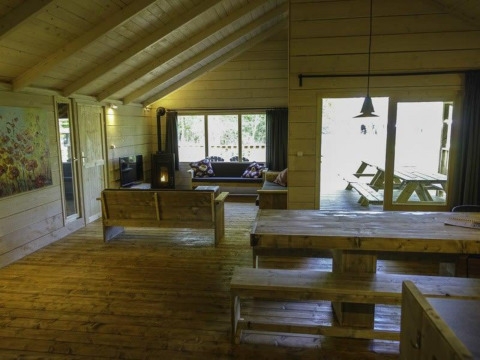 Interior de madera luminosa en la Glamping family lodge 10 de EuroParcs Ruinen, con grandes ventanales y muebles de madera.