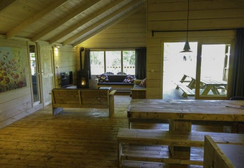 Intérieur en bois lumineux de la Glamping Family Lodge 10 à EuroParcs Ruinen avec grandes fenêtres et mobilier en bois.