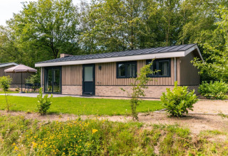Chalet Hackfort à EuroParcs Ruinen, Pays-Bas, entouré de verdure avec une terrasse et des sièges extérieurs.