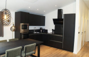Moderne, donkere keuken in chalet Hackfort bij EuroParcs Ruinen, Nederland, met eet- en zitgedeelte.