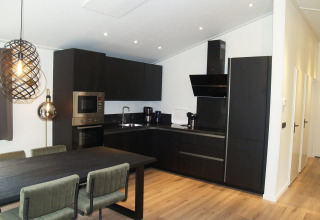Cuisine moderne sombre dans un chalet Hackfort à EuroParcs Ruinen, Pays-Bas, avec table à manger et lumière.