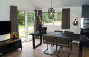 Modern dining area inside Chalet Hackfort at EuroParcs Ruinen, Netherlands, with large windows and decor.