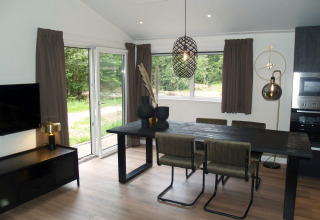 Modern dining area inside Chalet Hackfort at EuroParcs Ruinen, Netherlands, with large windows and decor.