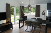 Moderne eetkamer in chalet Hackfort bij EuroParcs Ruinen, Nederland, met grote ramen en stijlvolle meubels.