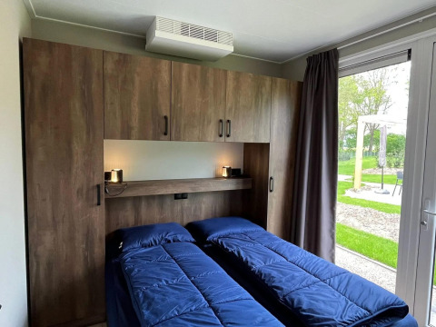 Dormitorio en el chalet Hackfort en EuroParcs Ruinen, Países Bajos, con dos camas y vista al jardín.