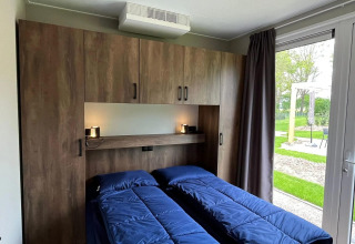 Chambre du chalet Hackfort à EuroParcs Ruinen aux Pays-Bas avec deux lits, placards et vue sur le jardin.