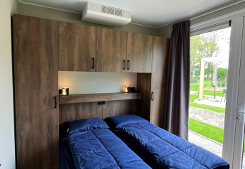 Slaapkamer in het Hackfort-chalet bij EuroParcs Ruinen in Nederland met twee bedden en tuinzicht.
