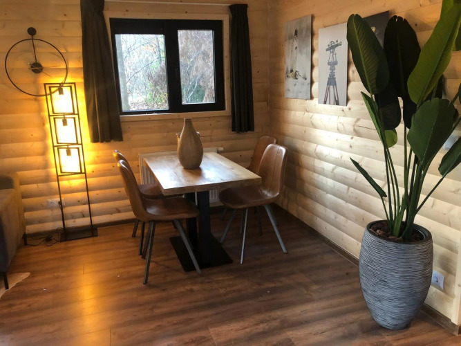 Gemütlicher Essbereich in einer Velthorst-Lodge, mit Holzvertäfelung, Pflanze und Kunst in De Wiltzangh, Niederlande.