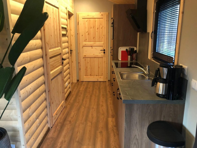 Modernes Lodge-Kücheninterieur mit Holzverkleidung, Holzboden, Fensterjalousien und Kaffeemaschine.