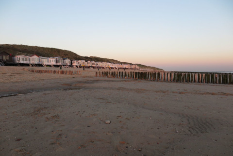 Strandhus ved solnedgang med klitter og hav i baggrunden, Dishoek 60, Zeeland, Holland.