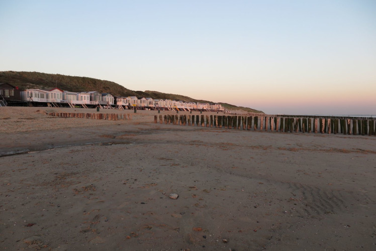 Strandhuisjes bij zonsondergang aan het strand met duinen, Dishoek 60, Zeeland, Nederland.