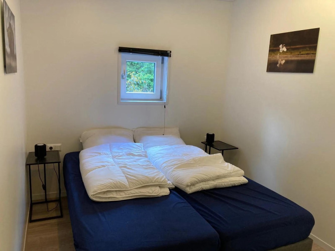 Ein einfaches Schlafzimmer in einer Lodge mit Doppelbett, zwei Nachttischen und kleinem Fenster über dem Bett.