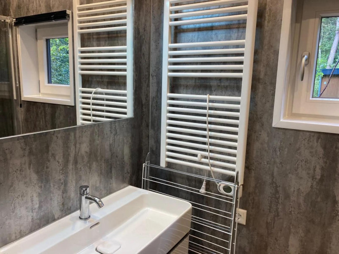 Modernes Badezimmer in einer Lodge mit Waschbecken, elektrischem Handtuchwärmer und kleinen Fenstern.