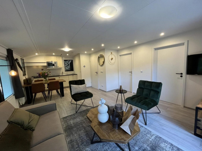 Modernes Glamping-Apartment mit stilvollem Wohnzimmer, Essbereich, Küche und gemütlichen Sesseln.