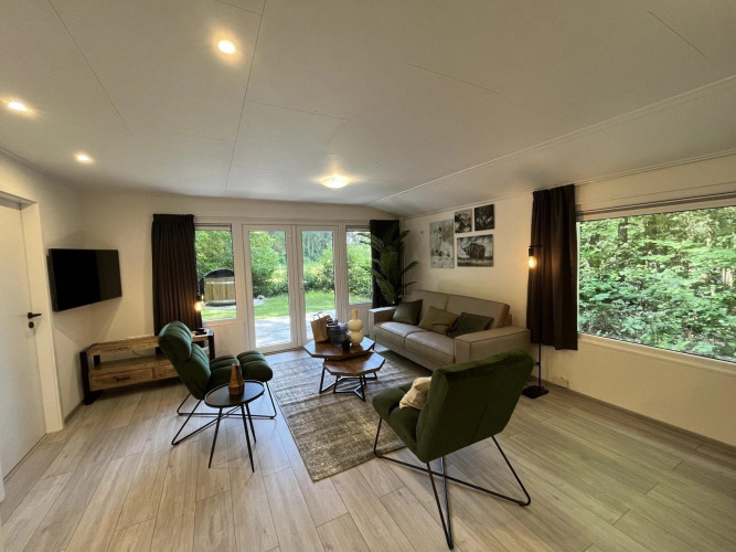 Moderne Glamping-Unterkunft mit stilvollem Wohnzimmer, großen Fenstern und Blick auf die Natur draußen.