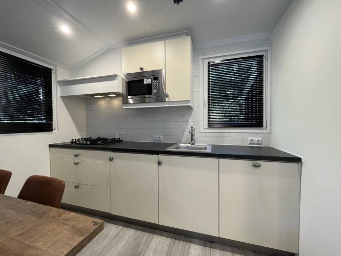 Modernes Glamping-Küchenbild mit schwarzen Arbeitsflächen, Gasherd, Spüle und Mikrowelle.