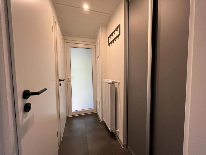 Flur in einer Glamping-Unterkunft mit Glastür, Wandhaken, Heizung und Schiebetürenschrank.