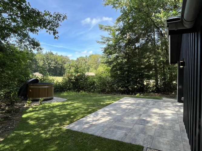 Terrasse und Whirlpool bei Stuga Hottub im Vakantiepark De Wiltzangh, umgeben von Waldlandschaft in den Niederlanden.