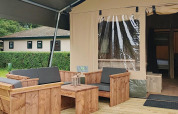 Buitenzitje bij een safaritentlodge op Molengroet in Nederland met houten meubels op het terras.