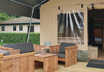 Area salotto esterna di una tenda safari al Molengroet nei Paesi Bassi, con arredi in legno visibili.