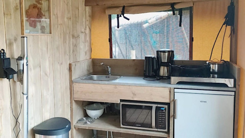 Lille tekøkken i Safari-telt ved Molengroet, Holland, med vask, komfur, kaffemaskine og mikrobølgeovn.