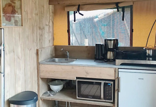 Piccola cucina in tenda Safari al Molengroet, Paesi Bassi, con lavello, fornello, caffettiera e microonde.