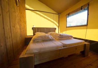 Indenfor en Safari-telt lodge på Molengroet i Holland, vises en dobbeltseng og træinteriør.