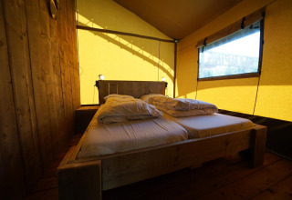 Interior de una tienda Safari en Molengroet, Países Bajos, con cama doble y decoración de madera.