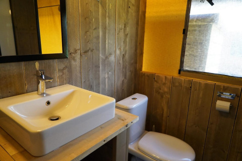 Badkamer met houten wanden, moderne wastafel, spiegel en toilet in een safaritent bij Molengroet, Nederland.